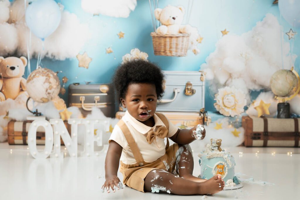 One-Year-Old Sitting Beside Birthday Cake During A Dallas Milestone Photography Session.