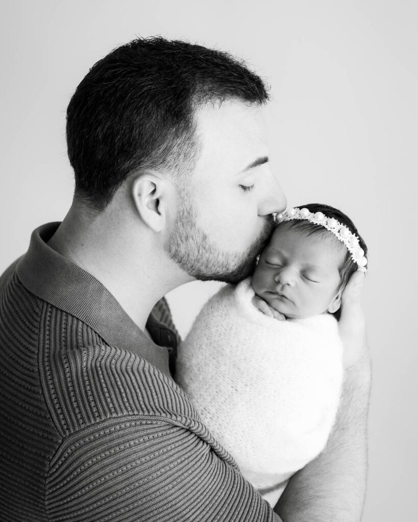 What Happens If My Baby Won’t Sleep During A Newborn Session? 19 Father Holding And Kissing His Newborn Daughter During A Studio Newborn Photography Session In Dallas