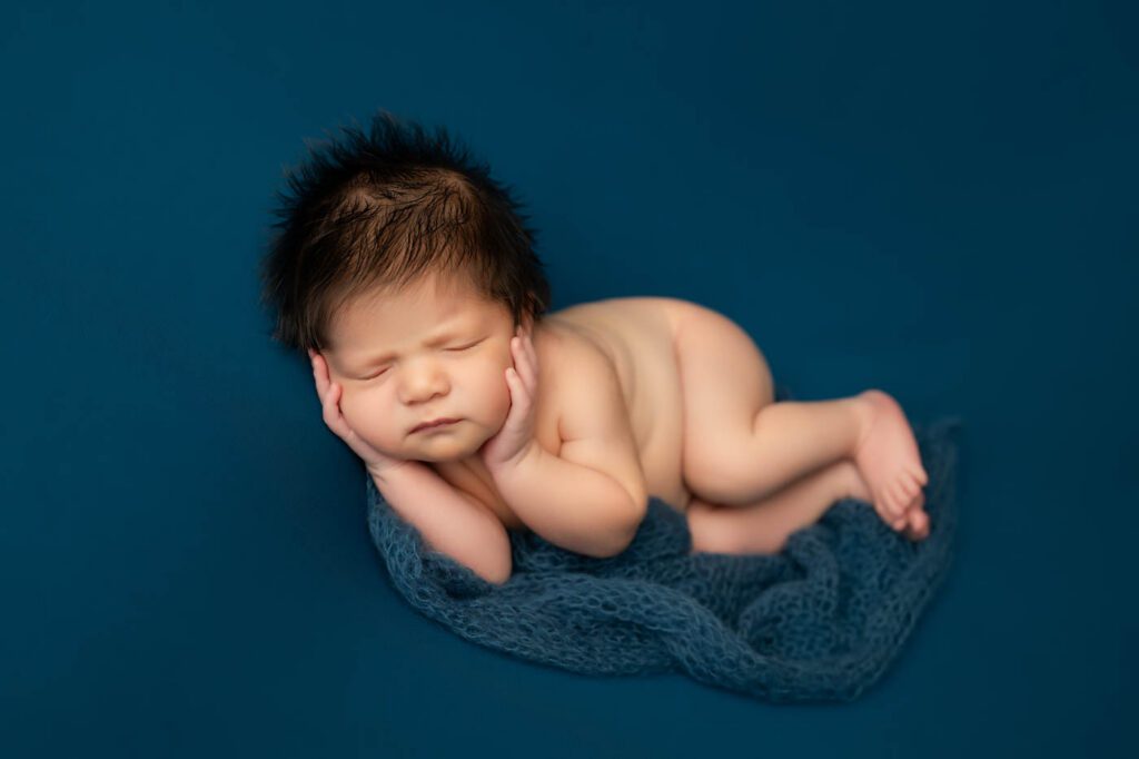 How To Choose A Newborn Photographer In Dallas | What Every Parent Should Know 13 Sleeping Newborn Baby Posed On A Deep Blue Backdrop During A Professional Dallas Newborn Photographer Studio Session.