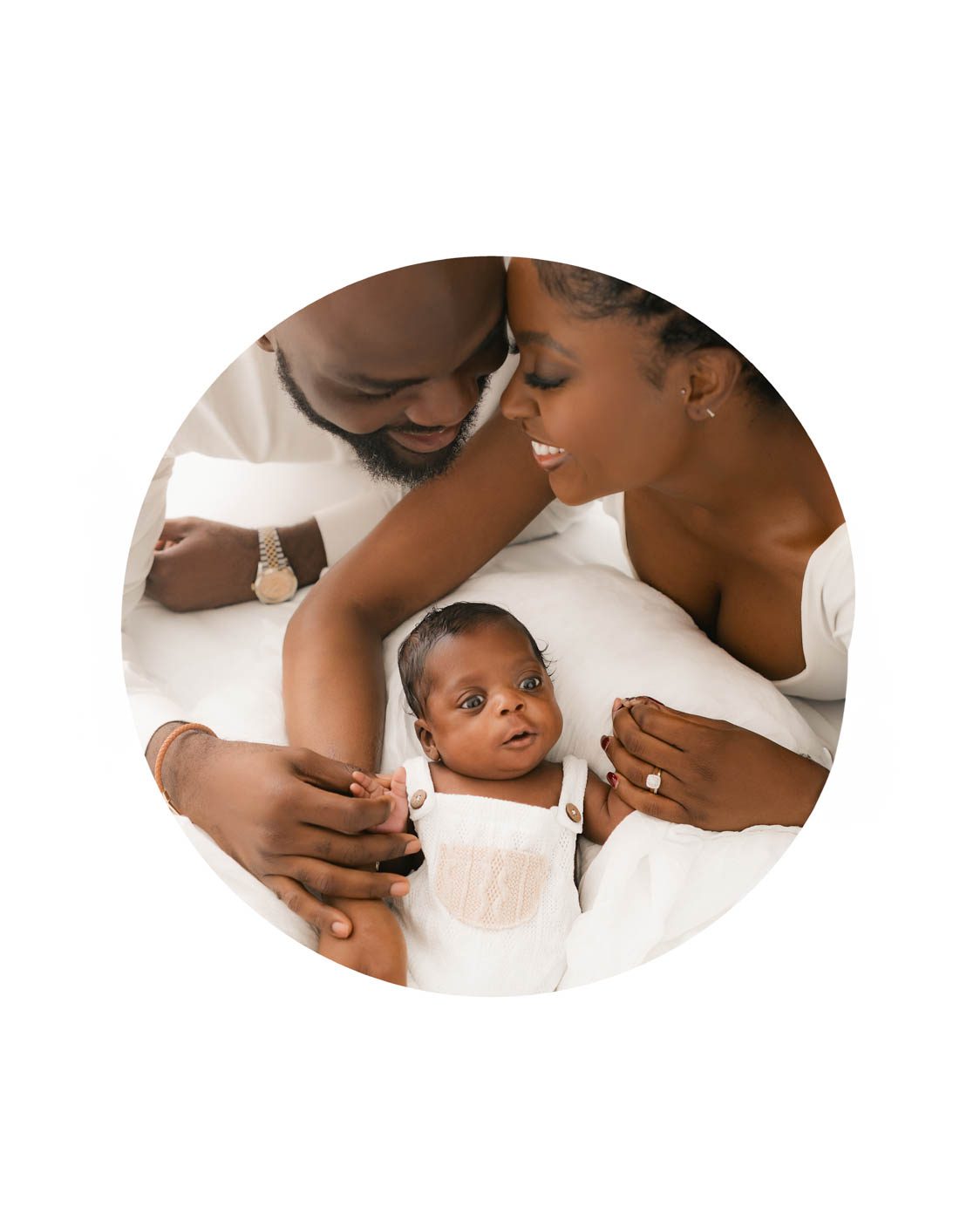 Newborn photographer in Dallas capturing a natural lifestyle family portrait with parents embracing their newborn baby in a bright white studio.